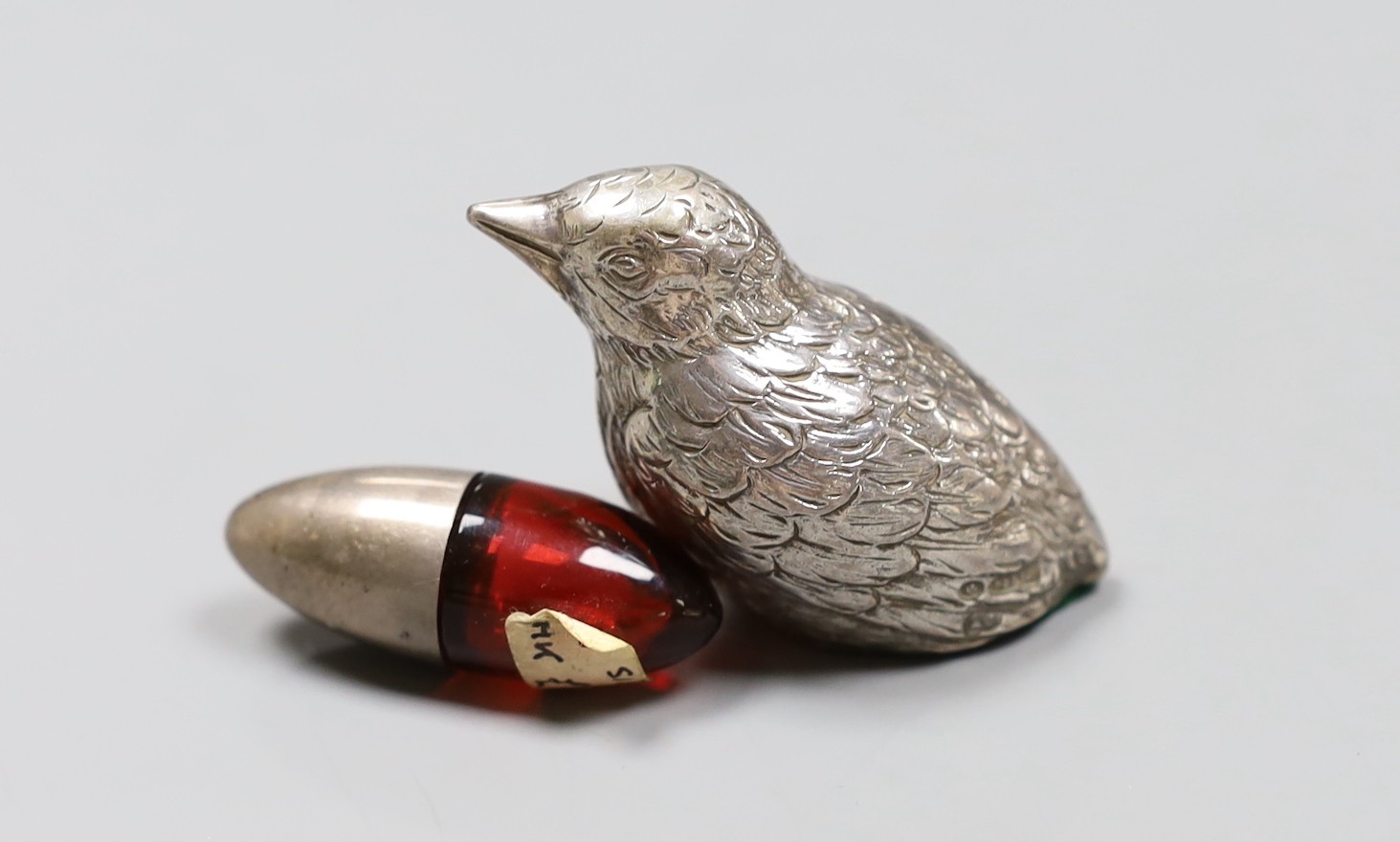An Edwardian silver mounted ruby glass scent bottle, 4cm and a silver overlaid bird paperweight, 5cm